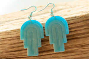 Love For Resin turquoise geometric arch drop earrings with a matte finish and hook-style backing on a wooden surface.