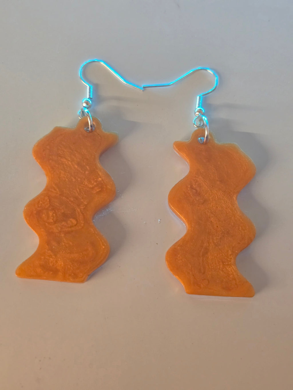 Love For Resin wavy dangle earrings in shimmering amber resin with silver-tone hooks and a fluid, organic silhouette.